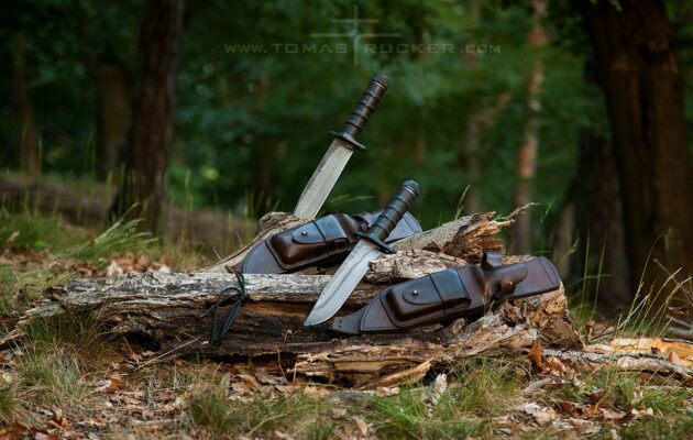 KNIVES by Tomas Rucker Two survival knives with hollow handles and leather gear sheaths in a forest setting by Tomas Rucker.