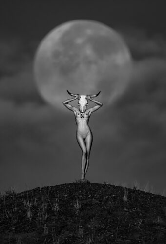 Totemism with a Moon Black and white fine art photography by Tomas Rucker showing a central human figure holding a horned animal skull under a giant full moon